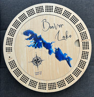 Circular wooden board with 'Beaver Lake' engraving and blue lake illustration on a dark fabric background